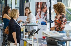 Auf dem Bild zu sehen ist das BiSS-Transfer Blended-Learning-Team, das an einem Ausstellungsstand auf den Fachtagen der BiSS-Akademie NRW die Fortbildungs- und Unterstützungsangebote für Lehrerinnen und Lehrer präsentiert.